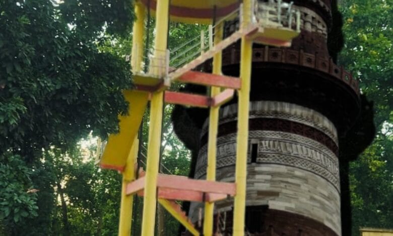 कोदोभाट में जल जीवन मिशन योजना का सूचना बोर्ड और क़ुतुब मीनार की प्रतिबिम्ब वाली प्रतीकात्मक तस्वीर